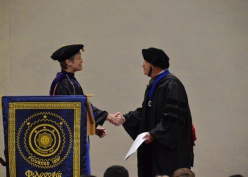 Michael Rafferty shaking hands with a dean after receiving his diploma